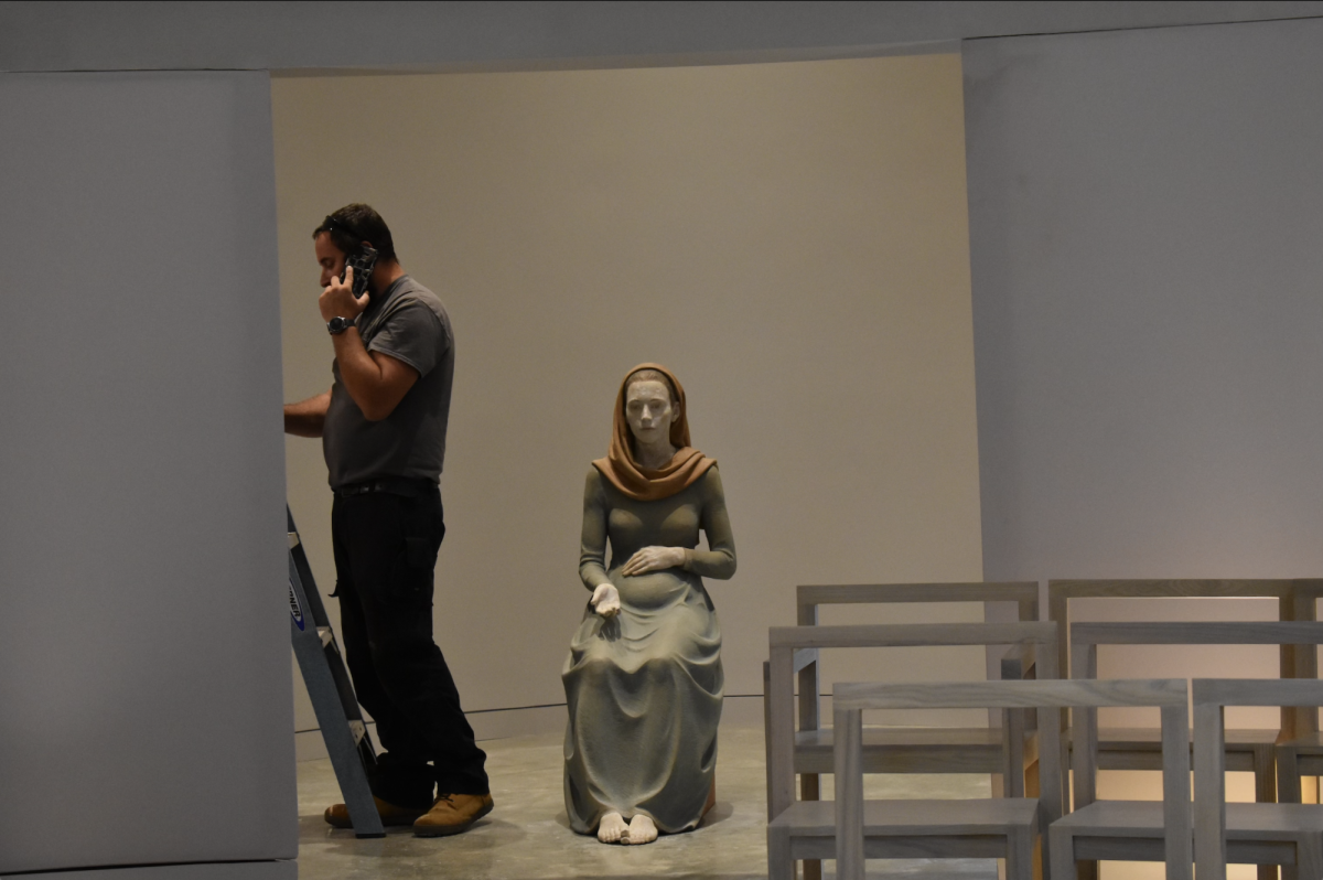 Construction worker stands next to statue Mother Mary in the new chapel.